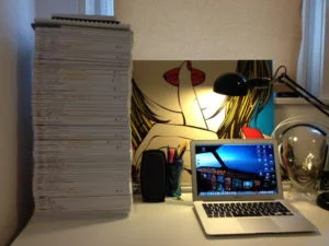 Stapel von Theorie-Skripten neben Laptop